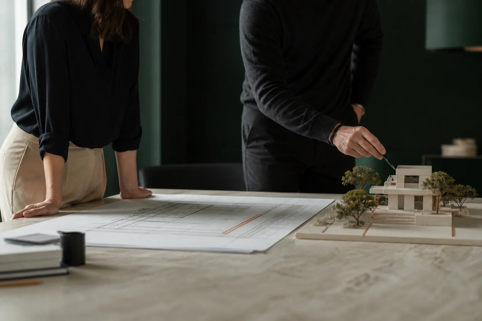 Two professionals reviewing architectural plans and a property model